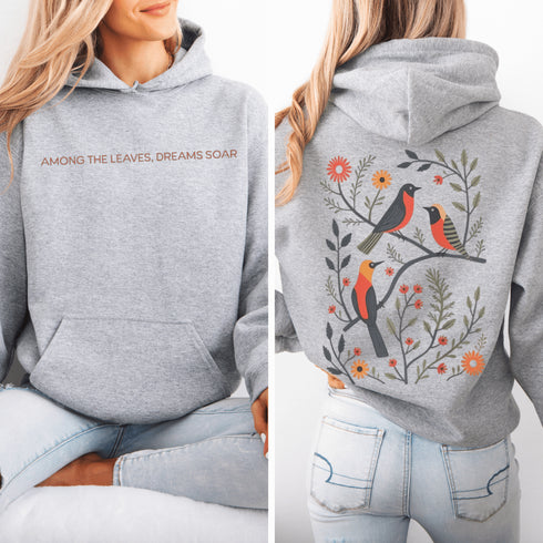 Wrap yourself in the charm of nature with our Among the Leaves Hoodie, a wearable piece of folk art that celebrates the harmony of birds, branches, and blooms.